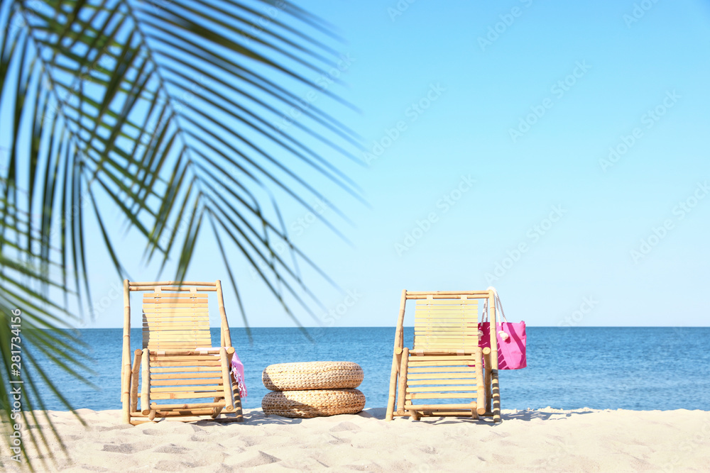 Wooden sunbeds and beach accessories on sandy shore