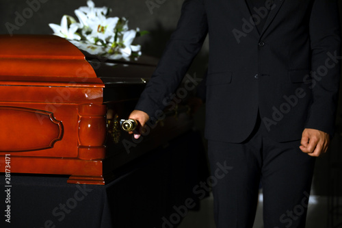 Obraz na płótnie Young man carrying wooden casket in funeral home, closeup