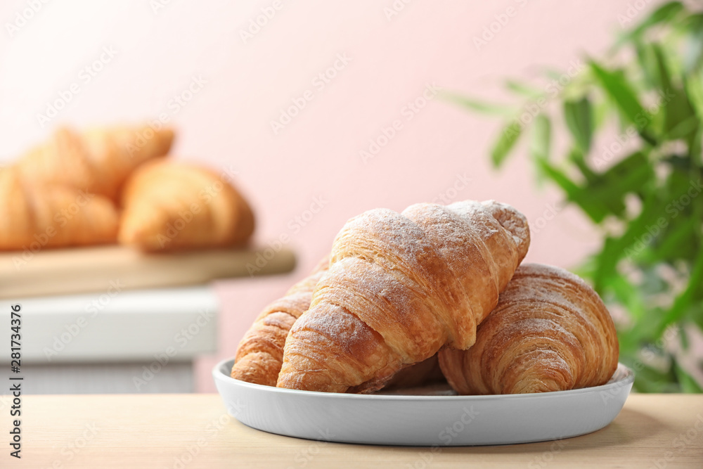 Plate of fresh croissants sprinkled with powdered sugar on table indoors, space for text. French pastry Plate of fresh croissants sprinkled with powdered sugar on table indoors, space for text. French pastry
