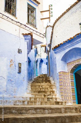 Stunning view of a narrow alleyway with the striking, blue-washed buildings. Chefchaouen, or Chaouen, is a city in the Rif Mountains of northwest Morocco. © Travel Wild