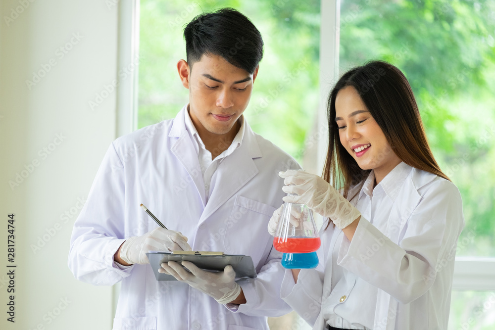 Couple of scientists working together in a laboratory, by doing experiments with various coloured chemical solutions in glass containers. Couple of scientists working together in a laboratory, by doing experiments with various coloured chemical solutions in glass containers.