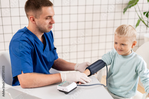 Wallpaper Mural Doctor measuring blood pressure of a little boy. Diagnostic, healthcare, medical service. Doctor pediatrician concept Torontodigital.ca