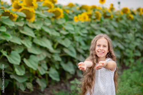 Beautiful portrait of a girl with long hair on a background of a field with sunflowers.