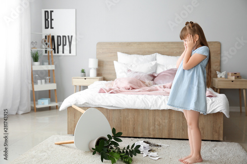 Vászonkép Little girl in room with dropped houseplant and paper pieces on carpet