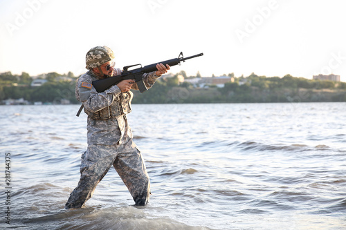 Soldier in camouflage taking aim in river