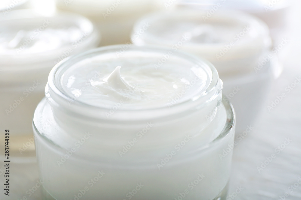 Jars of body cream on white table, closeup Jars of body cream on white table, closeup