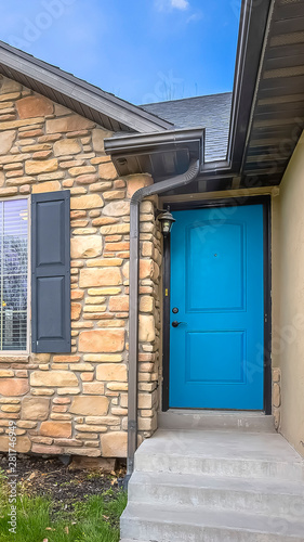Vertical frame Home with stairs blue front door stone wall and windows with wooden shutters