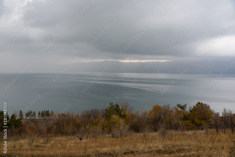The endless water expanses of the Lake Sevan on a cloudy day with a thunder cloud and clouds in the sky.