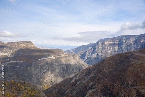 view of the mountain ranges on a bright sunny day with clouds in the sky and sun rays passing through the clouds  snow-covered tops of the mountain slopes on the horizon.