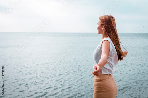 girl looks at the sea, arms outstretched.