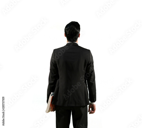 A man Standing against an empty wall wearing a Black suite and holding books | Teacher Back view