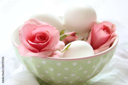 pink rose and eggs in a bowl on white background