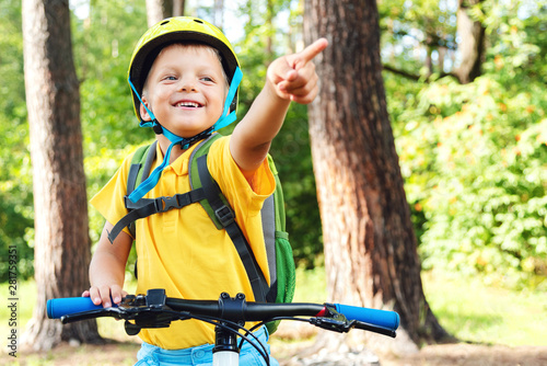 A boy in bright clothes on a bicycle gesture shows where to go next
