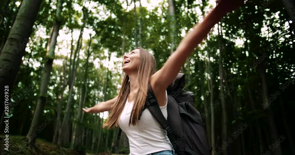 Beautiful lady hiker with backpack dressed in white t-shirt spinning around enjoying cool time in forest, amazing nature Beautiful lady hiker with backpack dressed in white t-shirt spinning around enjoying cool time in forest, amazing nature