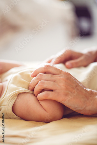 Mom holds baby by hand, touching baby. Close-up