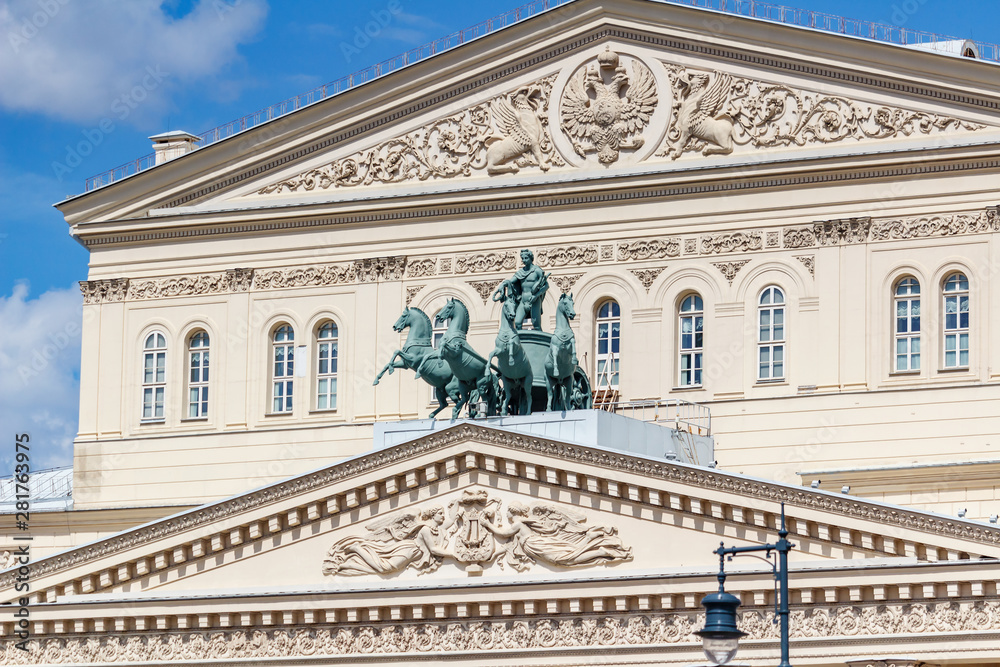 Facade of Bolshoi Theatre in Moscow closeup at sunny day against blue sky with white clouds