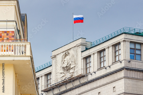 Waving flag of Russian Federation on the roof of building of State Duma of Russian Federation in Moscow against blue sky