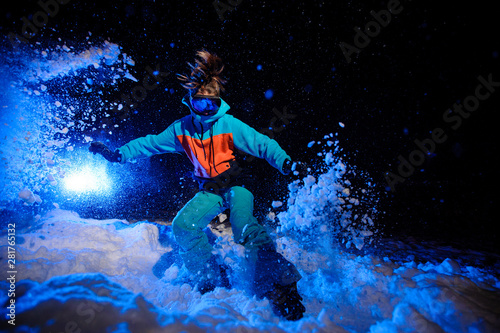 Foto Active female snowboarder dressed in a orange and blue sportswear riding on the