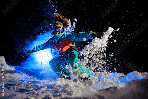Snowboarder girl dressed in a orange and blue sportswear making tricks on the snow