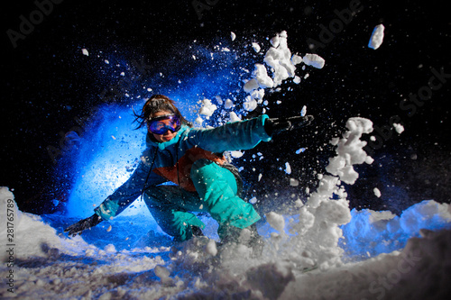 Snowboarder girl dressed in a orange and blue sportswear makes tricks on the snow