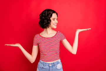 Portrait of her she nice attractive lovely charming pretty cheerful cheery content glad wavy-haired girl holding ad advert on two palms isolated over bright vivid shine red background