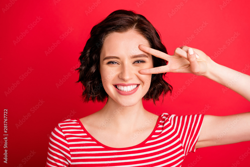 Photo of cute rejoicing woman imagining as if her fingers were scissors while isolated with red background