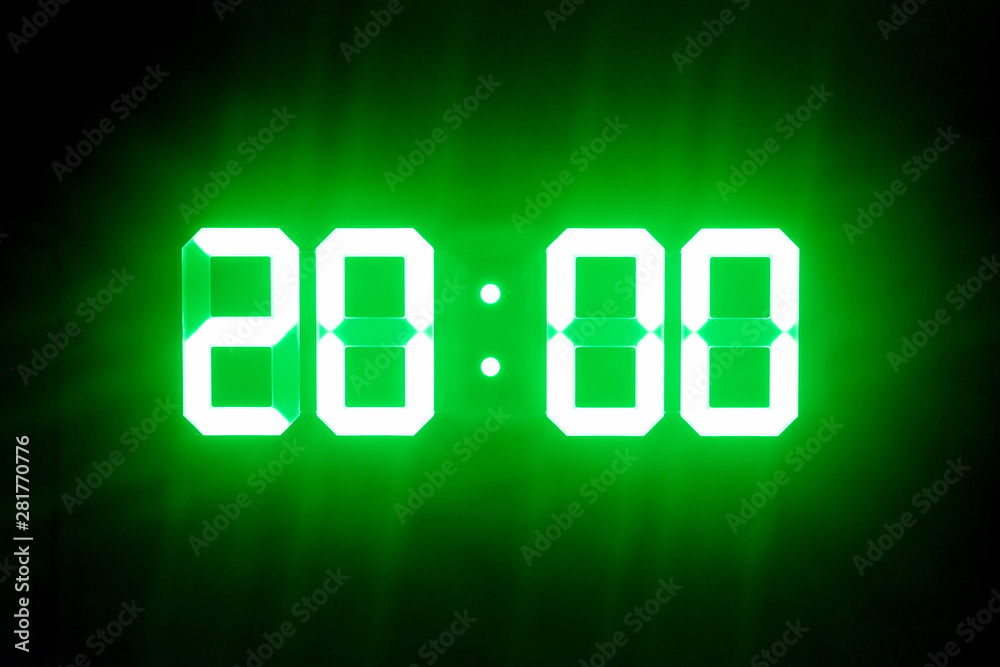 Green glowing digital clocks in the dark show 20:00 time Green glowing digital clocks in the dark show 20:00 time