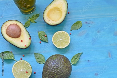 Top table concept with avocado, olive oil, limes and mint leaves on blue background. Copy text space