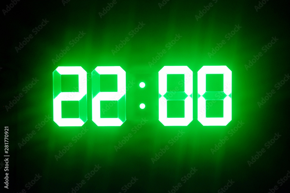Green glowing digital clocks in the dark show 22:00 time Green glowing digital clocks in the dark show 22:00 time