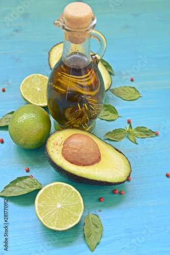 Concept dish with natural avocado, olive oil, limes and mint leaves on blue background. Vertical.