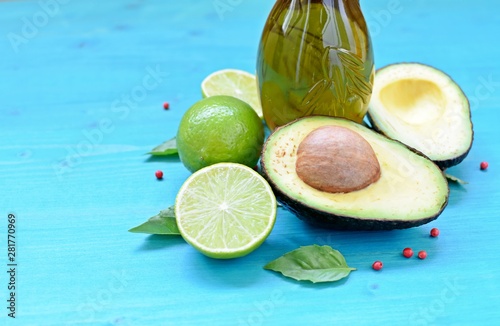 Concept dish with natural avocado, olive oil, limes and mint leaves on blue background.
