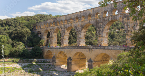 Pont du Gard is a Roman three-tiered aqueduct built in Provence (France) over the river Gardon. This view of the highest roman bridge in Europe is taken a sunny summer day. – Image