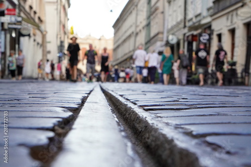 rails for city trams in the middle of the pavement. people walking in the old town in the soft sunlight