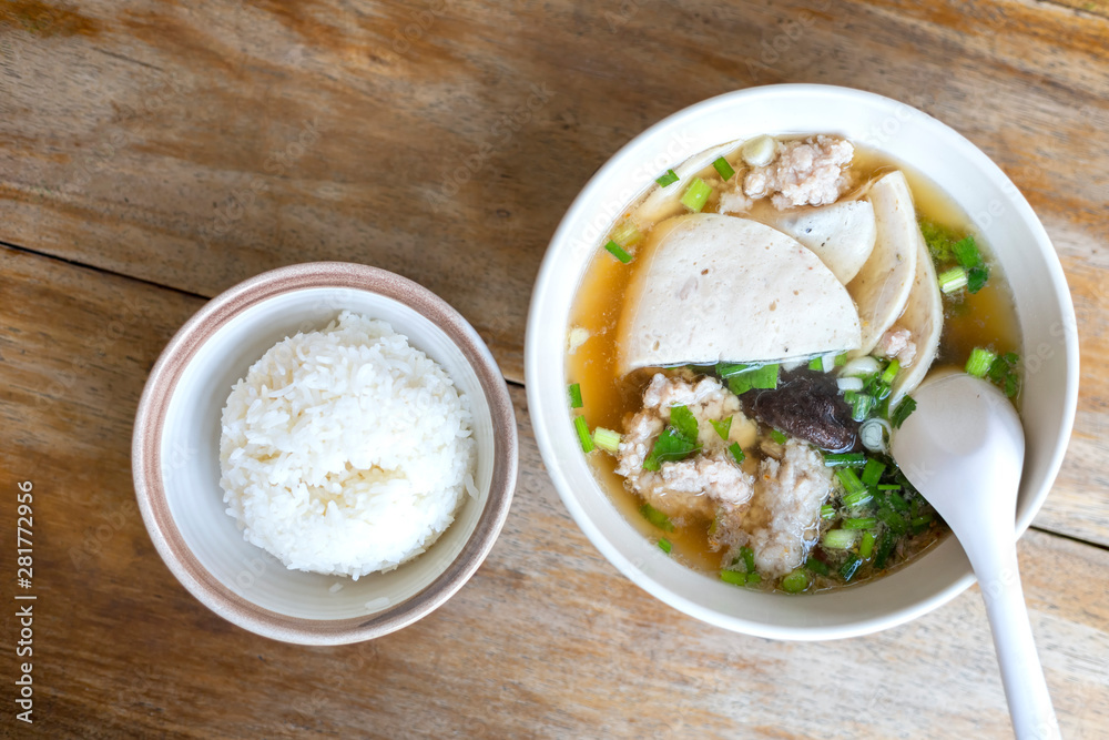 Top view Soup with pock, pock stick, mushroom, vegetable in white bowl near have rice in small bowl on wood table. with copy space for text or design Top view Soup with pock, pock stick, mushroom, vegetable in white bowl near have rice in small bowl on wood table. with copy space for text or design