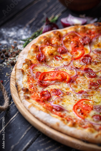 Aromatic pizza with hunting sausages, onions and tomatoes