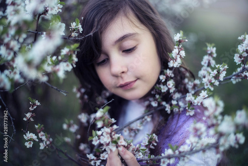 Portrait of a beautiful girl on the background of flowering branches of cherry. © leonidis97
