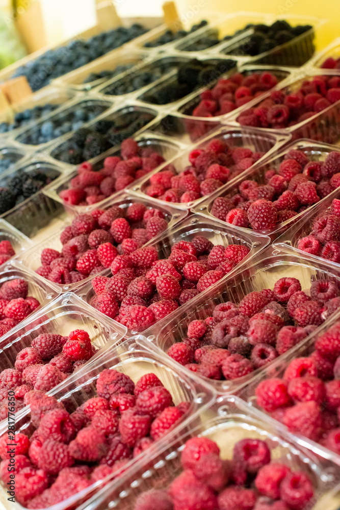 Raspberries and blueberries on shelf in the market.