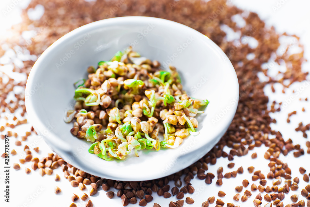Germinated green buckwheat in a white bowl and croup on a white background. Vegetarianism. Vitamins. Fagopyrum Germinated green buckwheat in a white bowl and croup on a white background. Vegetarianism. Vitamins. Fagopyrum