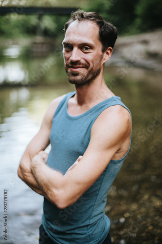 portrait of smiling man standing in the middle of a river