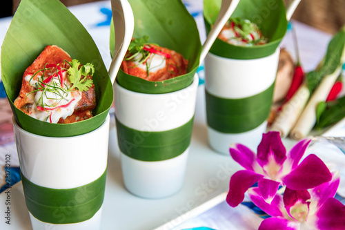 Hot curry decorated with banana leaves and purple flower put on a desk use for poster restaurant and web background.