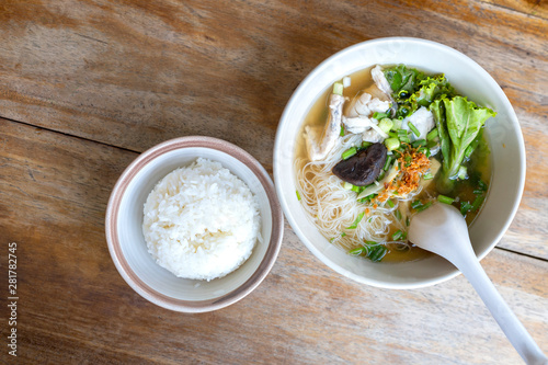 Bilde på lerret Soup with thin noodle, pock, pock stick, mushroom, vegetable in white bowl near have rice in small bowl on wood table