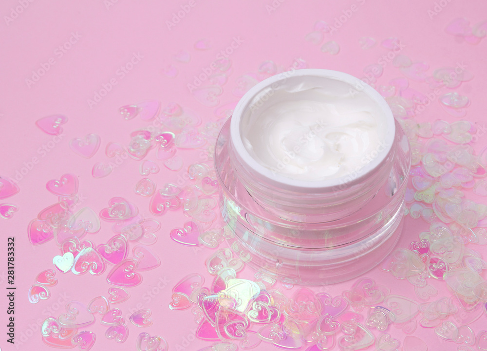 Cosmetic cream lotion jar on pink holographic heart confetti sparkles background with copy space. Cosmetic cream lotion jar on pink holographic heart confetti sparkles background with copy space.