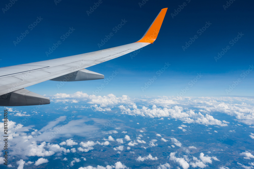 Fototapeta premium Wing of an airplane flying above the clouds