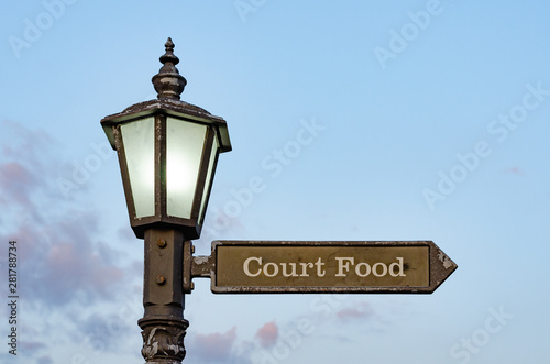 Close-up  of street lighting pole with iron sign to the food court .