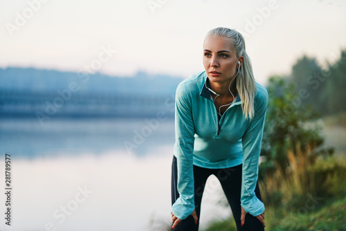 Beautiful athletic woman taking break during morning jog on autumn day