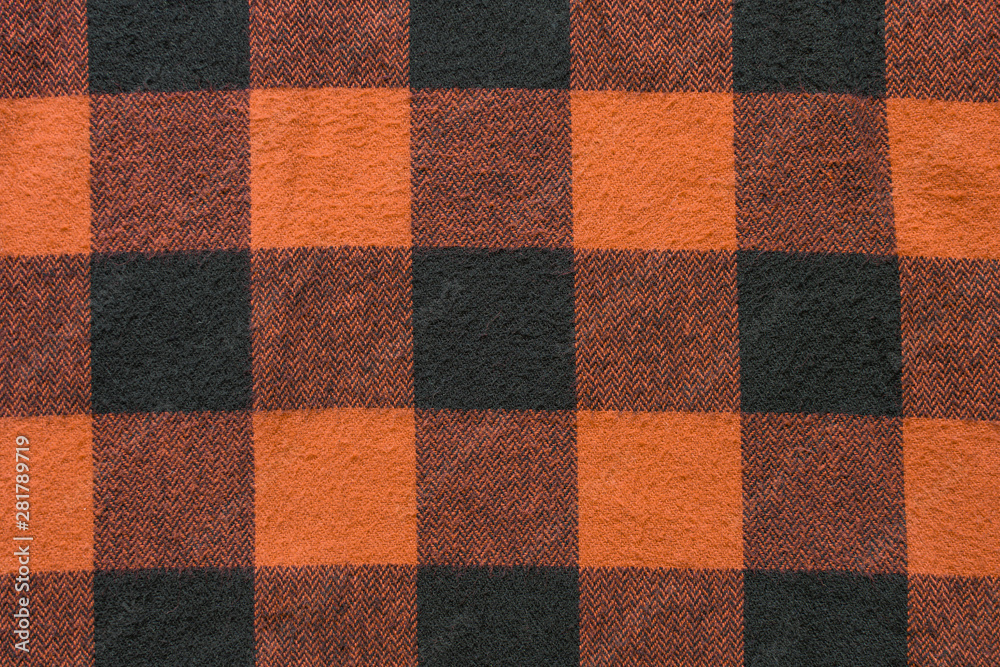Fabric with black and orange cages pattern. Plaid material. Clothes background