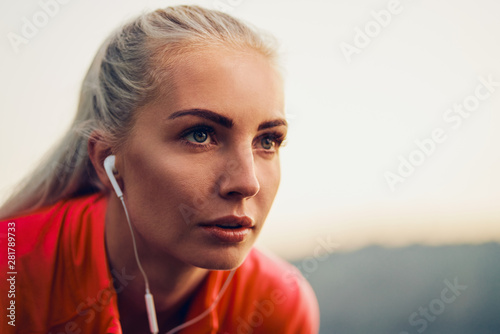 Close up of female runner in earphones looking away during morning workout © baranq