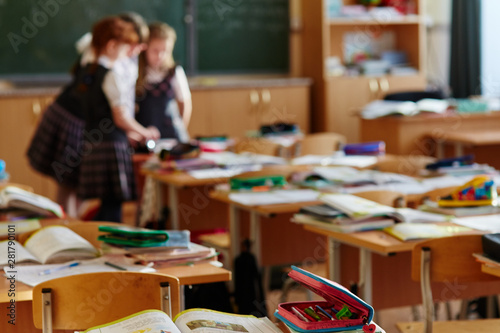 The children left their satchels and notebooks on the tables and went to recess. Three small students stayed in class to discuss the lessons.