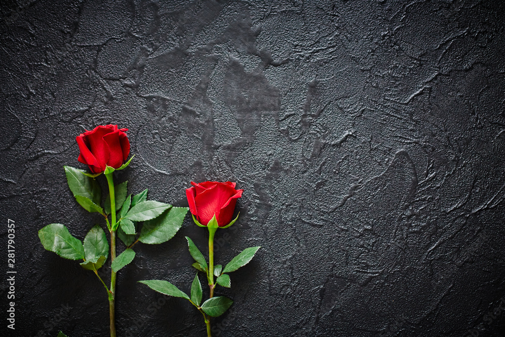Two red roses on a dark, black stone background. Place for text Two red roses on a dark, black stone background. Place for text