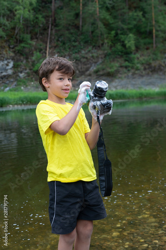 9 year old boy washes the camera with soap and a sponge while standing in the water. .wrong cleaning the camera and lens photo